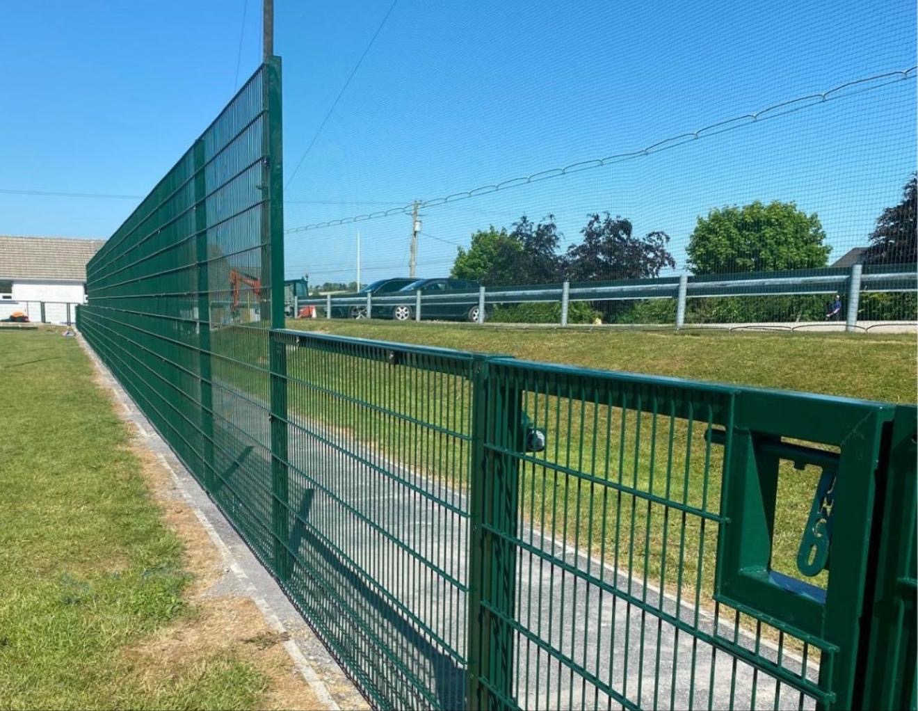 Tall green mesh security fencing with access gate